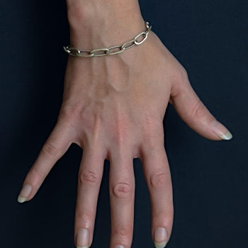 Long Oval Link Bracelet on model hand on navy blue background
