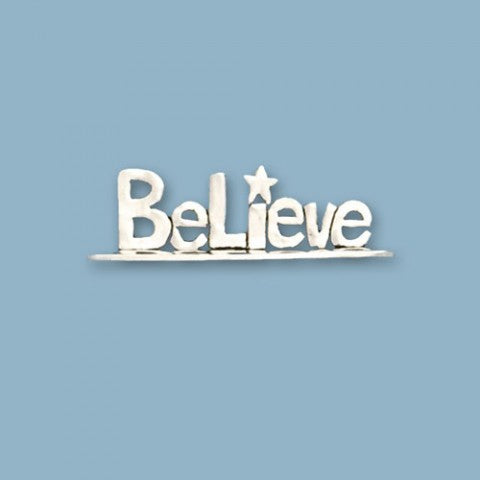 A silver metal plaque with the word 'BELIEVE' and a star symbol, against a blue background.