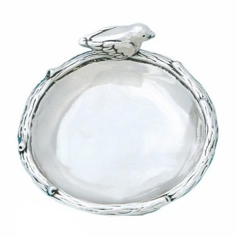 A silver pewter dish with a whimsical bird design on it, featuring a bird sitting on a branch.
